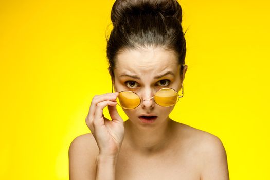 pretty woman with bare shoulders yellow glasses emotions cropped view. High quality photo