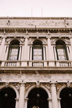 Vintage ornate windows and columns, venetian style, on fragment of building's luxurious building in Venice. Traditional ancient medieval gothic style