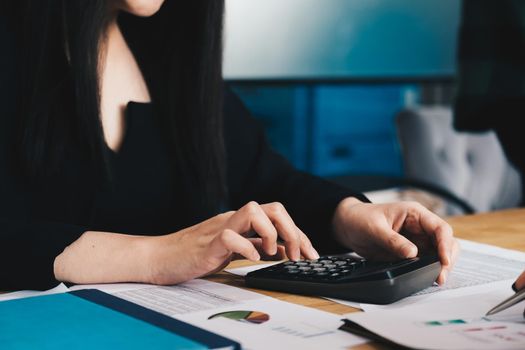 Close up of businessman or accountant hand working on calculator to calculate financial data report, accountancy document and laptop computer at office, business concept