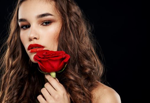 romantic woman on black background with red flower in her hands. High quality photo