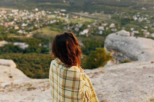 red-haired woman trail on the shoulders in the mountains in nature and the village in the background. High quality photo