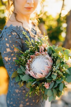 The bride in a stylish blue dress with wedding bouquet standing outdoors, close-up. High quality photo