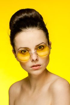 brunette with bare shoulders yellow glasses clear skin model. High quality photo