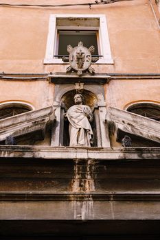 Close-ups of building facades in Venice, Italy. Ancient stone statue above the door.