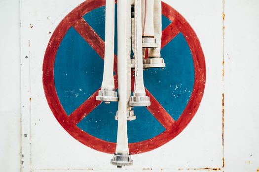 Fire hoses amid metal wall with parking sign banned