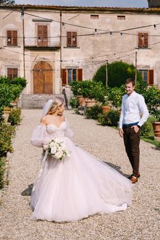 The wedding couple walks in the garden. Lovers of the bride and groom. Wedding in Florence, Italy, in an old villa-winery.