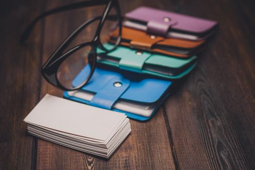 business card holders and a pack of white paper on a wooden background glasses with black frames. High quality photo