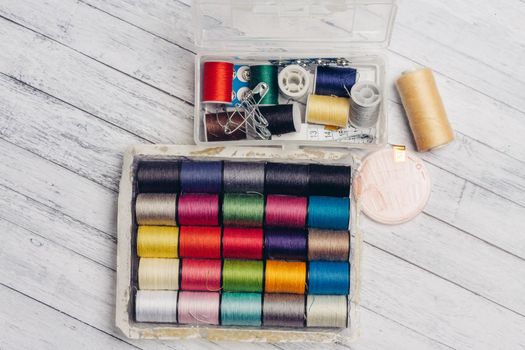 ball of multicolored threads in a box and sewing supplies needles and pins on a wooden table. High quality photo