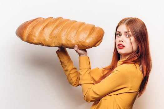 woman in a yellow shirt with a huge loaf in her hands a flour product light background. High quality photo