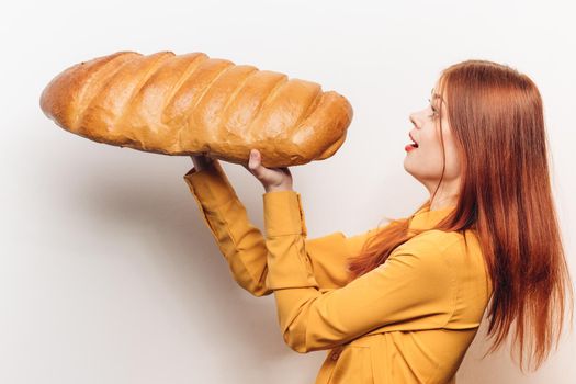 woman in a yellow shirt with a huge loaf in her hands a flour product light background. High quality photo