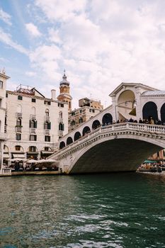 The beautiful Ponte di Rialto Bridge over Central Grand Canal in Venice, Italy, with shops, beautiful views and lots of people. Near boat station of the same name, the street leads to San Marco
