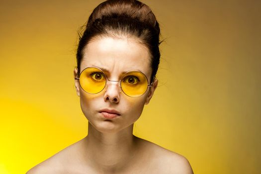 woman with bare shoulders yellow glasses collected hair emotions. High quality photo