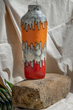 Orange and Red handmade ceramic vase on white textured table cloth.  Home decor, Copy space, Selective focus.