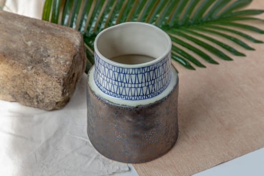 Handmade ceramic vase on white textured table cloth. Home decor, Copy space, Selective focus.