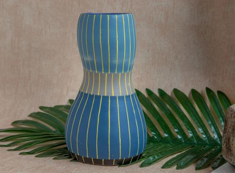 Blue and Yellow handmade ceramic vase on white textured table cloth.  Home decor, Copy space, Selective focus.