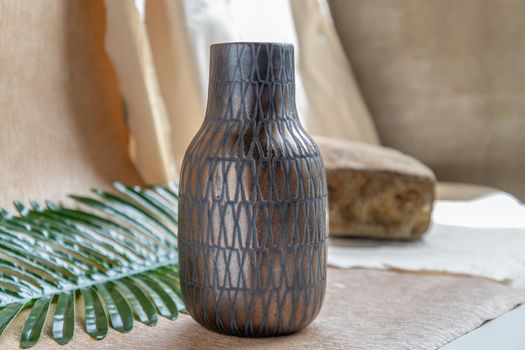 Copper color handmade ceramic vase on white textured table cloth. Home decor, Copy space, Selective focus.