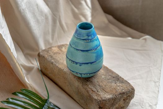 Blue handmade ceramic vase on white textured table cloth. Home decor, Copy space, Selective focus.
