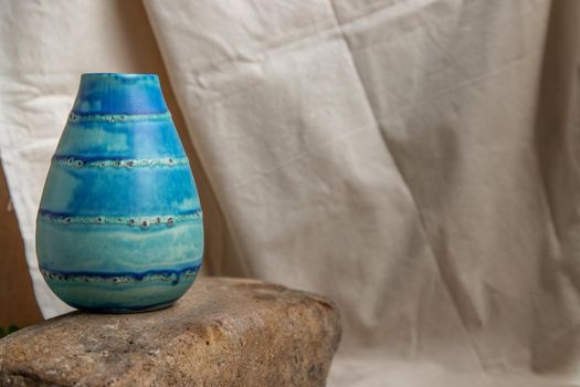 Blue handmade ceramic vase on white textured table cloth. Home decor, Copy space, Selective focus.