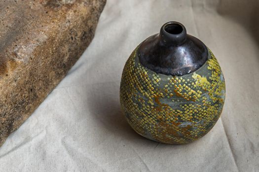 Yellow handmade ceramic vase on white textured table cloth. Home decor, Copy space, Selective focus.