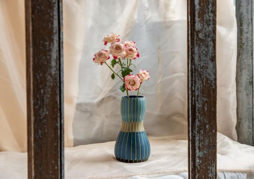 Bouquet of flower in Blue handmade ceramic vase on Blush textured table cloth. Home decor, Copy space, Selective focus.