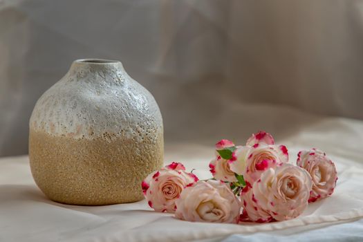 White and Yellow handmade ceramic vase with Bouquet of flower on Blush textured table cloth. Home decor, Copy space, Selective focus.