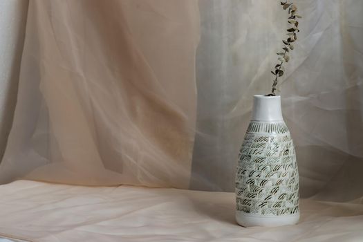 Dried flowers in White ceramic vase bottle shape on Blush textured table cloth. Home decor, Copy space, Selective focus.