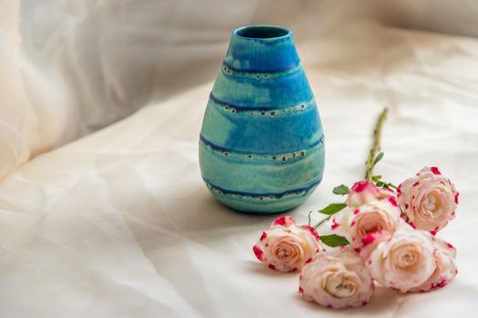 Blue handmade ceramic vase with Bouquet of flowers on Blush textured table cloth. Home decor, Copy space, Selective focus.