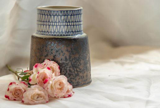 Blue handmade ceramic vase with Bouquet of flowers on Blush textured table cloth. Home decor, Copy space, Selective focus.