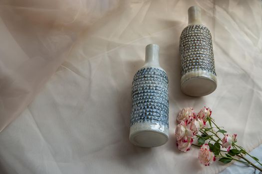 Two handmade ceramic vase bottle shape with Bouquet of flowers on Blush textured table cloth. Home decor, Copy space, Selective focus.