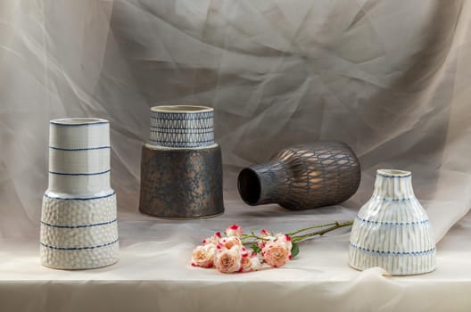 Four handmade ceramic vase with Pink flower on Blush textured table cloth. Home decor, Copy space, Selective focus.