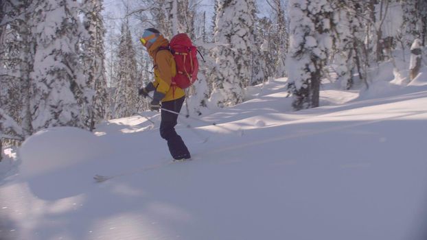 A man riding down the hill in a snowy forest, side view. Freeride in Siberia.