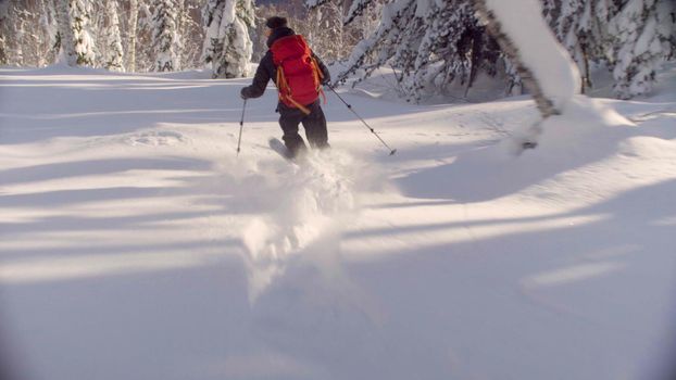 A man riding down the hill in a snowy forest, side view. Freeride in Siberia.