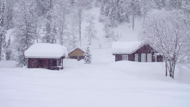 Snowfall in skitouring lodge in Siberia. Houses covered with snow