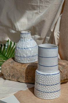 Two white handmade ceramic vases on white textured table cloth.  Home decor, Copy space, Selective focus.