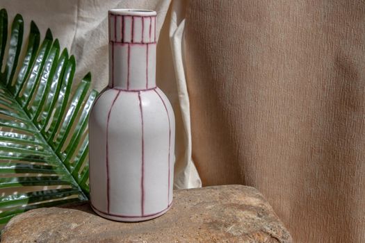 White and Pink handmade ceramic vase on white textured table cloth.  Home decor, Copy space, Selective focus.