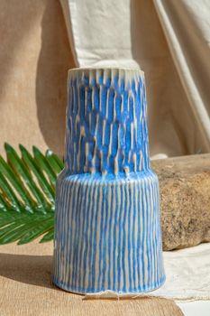 White and Blue handmade ceramic vase on white textured table cloth.  Home decor, Copy space, Selective focus.