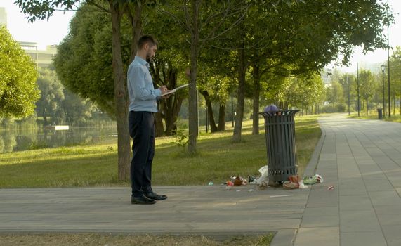 Inspector near the trash can and writing something in a notebook.