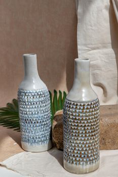 Two white and blue handmade ceramic vases on white textured table cloth.  Home decor, Copy space, Selective focus.