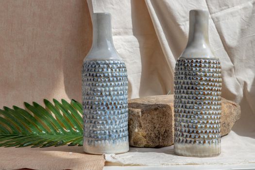 Two white and blue handmade ceramic vases on white textured table cloth.  Home decor, Copy space, Selective focus.