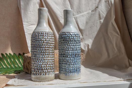 Two white and blue handmade ceramic vases on white textured table cloth.  Home decor, Copy space, Selective focus.