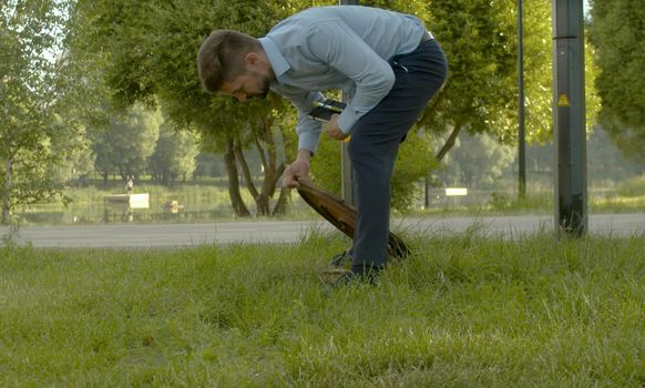 Inspector in business suit checking the manhole cover in the park