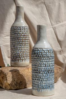 Two white and blue handmade ceramic vases on white textured table cloth.  Home decor, Copy space, Selective focus.