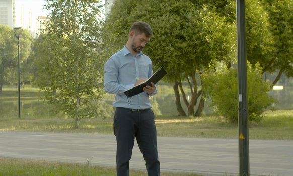 Inspector in business suit making notes in the diary in the park