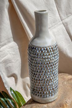 White and Blue handmade ceramic vase on white textured table cloth.  Home decor, Copy space, Selective focus.