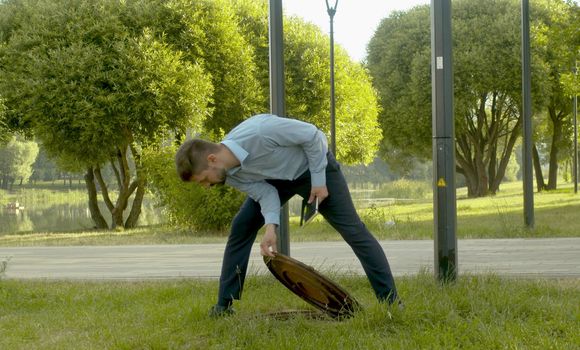 Inspector in business suit checking the manhole cover in the park