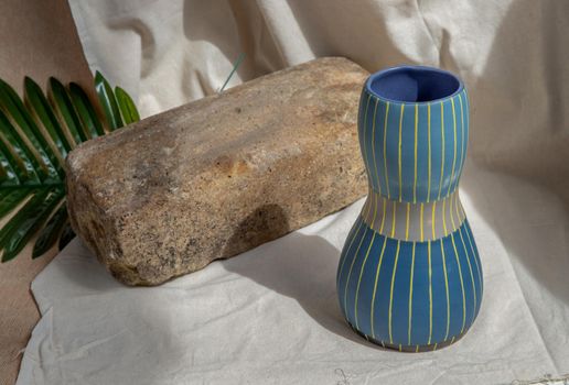 Blue and Yellow handmade ceramic vase on white textured table cloth.  Home decor, Copy space, Selective focus.
