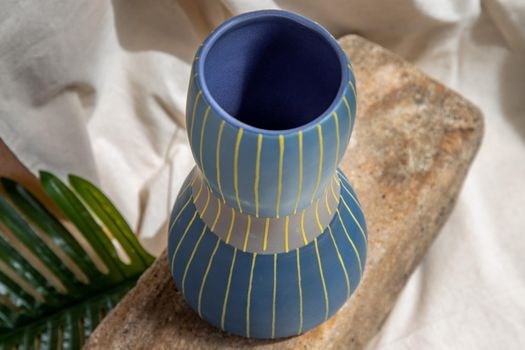 Blue and Yellow handmade ceramic vase on white textured table cloth.  Home decor, Copy space, Selective focus.