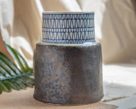 Handmade ceramic vase on white textured table cloth. Home decor, Copy space, Selective focus.