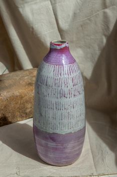 White and Pink Handmade ceramic vase on white textured table cloth. Home decor, Copy space, Selective focus.