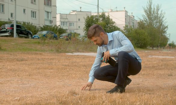 Incorrectly planted lawn. The grass dried up. Ecological inspector looks at the grass. Check of planting in the city park